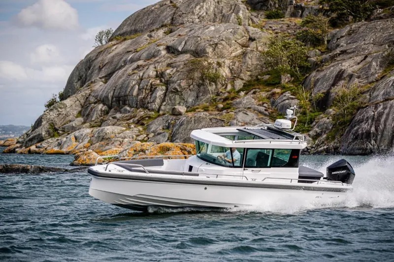 Slide: The Image of 2022 Axopar 28 Cabin boat on trailer under blue sky. - 1