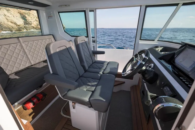 Slide: The Image of 2022 Axopar 28 Cabin dashboard with navigation controls and steering wheel. - 11