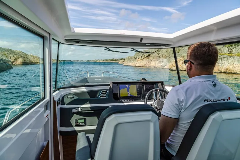 Slide: The Image of 2022 Axopar 28 Cabin boat on trailer, sunny day, palm trees in background. - 6