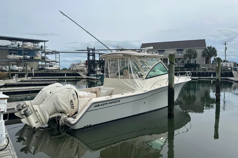 Slide: The Image of 2024 Grady-White Express 330 boat docked in a marina, featuring twin Yamaha engines. - 2