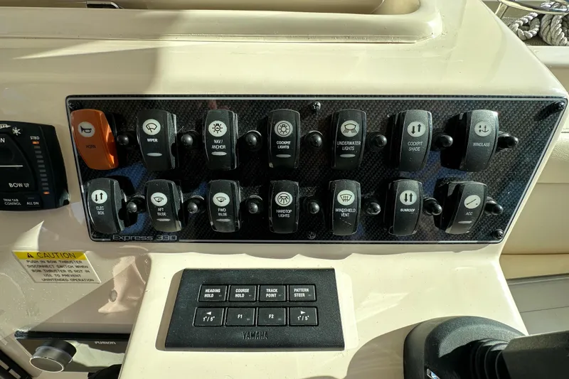 Slide: The Image of 2024 Grady-White Express 330 control panel with various switches and buttons. - 23
