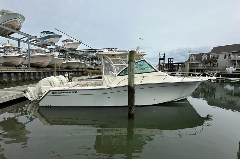 Slide: The Image of 2024 Grady-White Express 330 boat docked in a marina, surrounded by other vessels. - 3