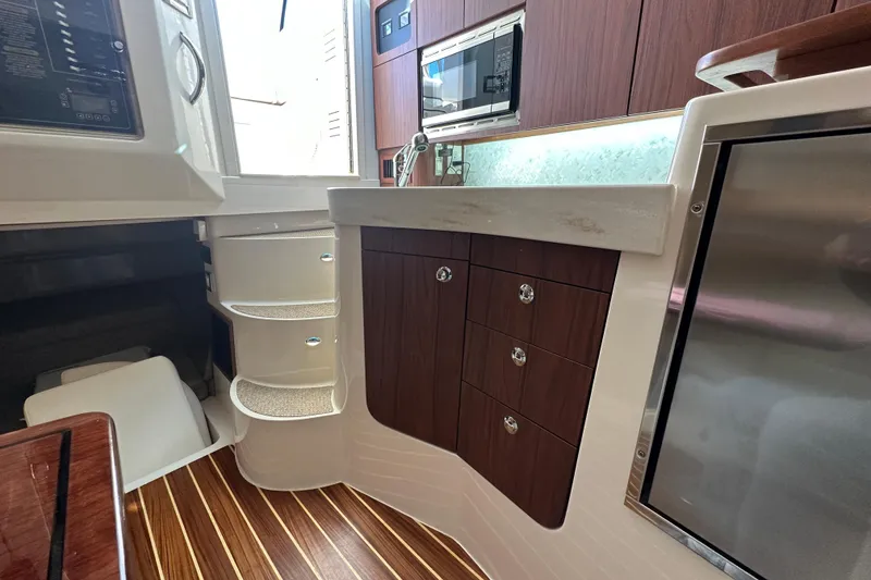 Slide: The Image of 2024 Grady-White Express 330 interior with kitchenette, wood cabinets, and modern appliances. - 31