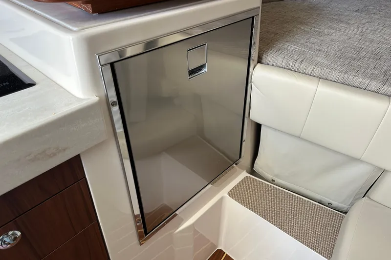 Slide: The Image of 2024 Grady-White Express 330 interior with stainless steel fridge and cushioned seating. - 35