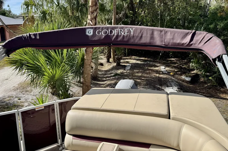 Slide: The Image of 2022 Godfrey Sweetwater 2286 C boat with canopy, surrounded by lush greenery. - 13