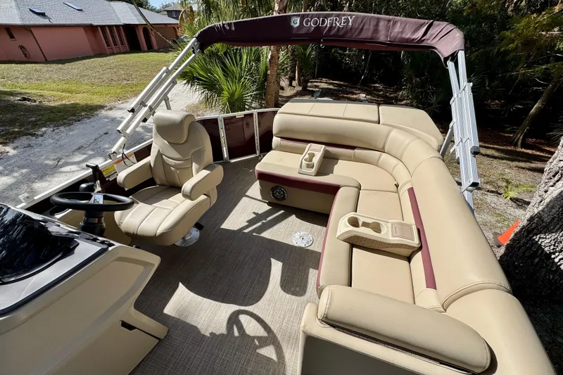 Slide: The Image of 2022 Godfrey Sweetwater 2286 C pontoon boat interior with beige seating and steering console. - 6