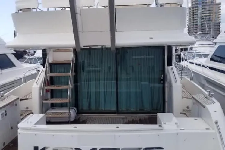 Slide: The Image of 2010 Fairline Squadron 55 yacht stern view with blue curtains and docked boats nearby. - 8