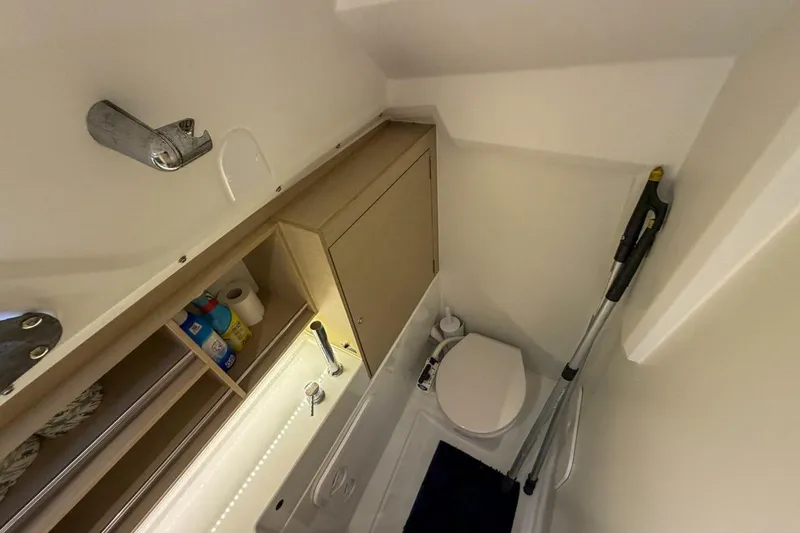 Slide: The Image of Compact bathroom in 2021 Beneteau Oceanis 30.1 yacht with storage and cleaning supplies. - 10