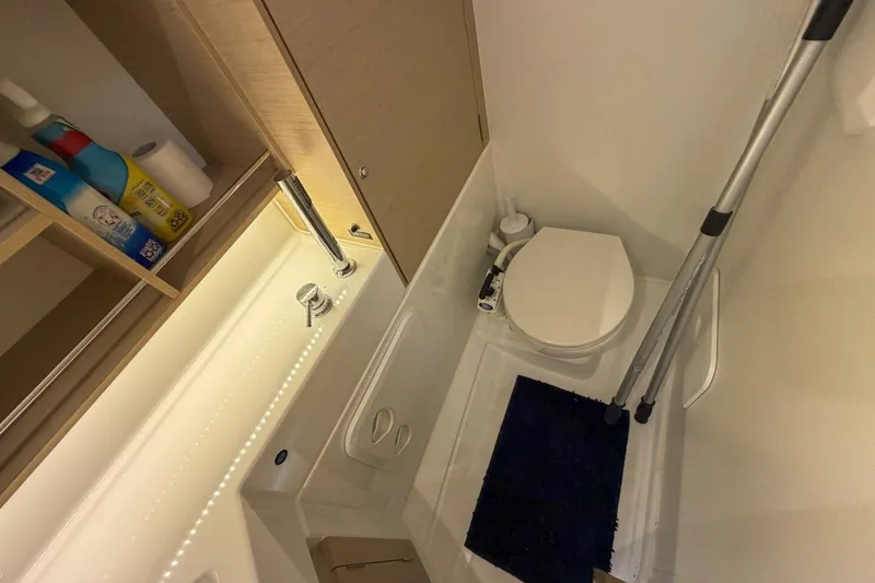 Slide: The Image of Bathroom interior of 2021 Beneteau Oceanis 30.1 yacht, featuring toilet and cleaning supplies. - 11