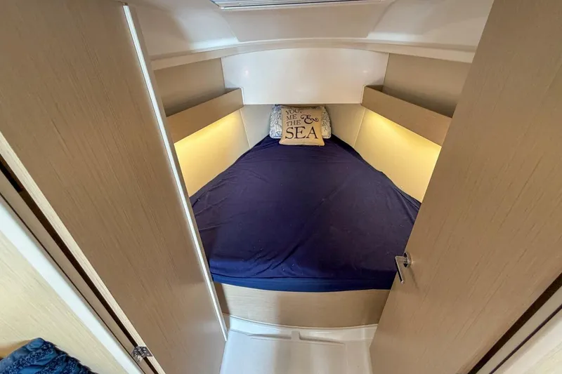 Slide: The Image of Cozy cabin interior of 2021 Beneteau Oceanis 30.1 with blue bedding and decorative pillow. - 15
