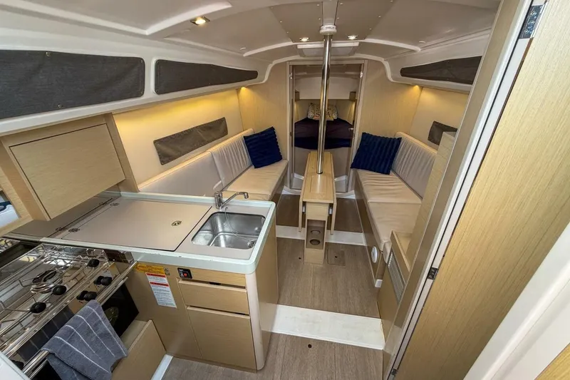 Slide: The Image of Interior of 2021 Beneteau Oceanis 30.1 yacht with modern kitchen and cozy seating. - 2