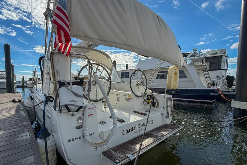 Slide: The Image of 2021 Beneteau Oceanis 30.1 sailboat docked, featuring American flag and clear blue sky. - 32