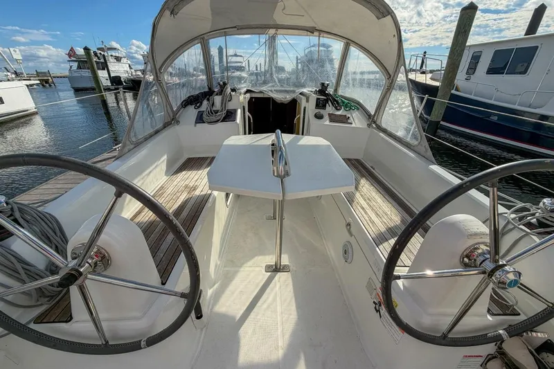Slide: The Image of 2021 Beneteau Oceanis 30.1 sailboat cockpit with dual steering wheels and marina view. - 41