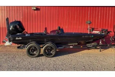 Slide: The Image of 2020 Bass Cat Eyra Premium boat, black, parked beside a red wall. - 0