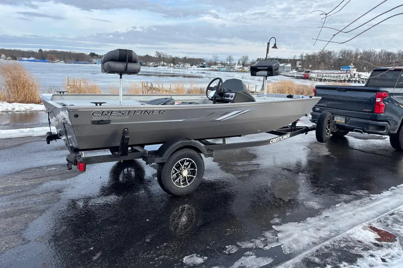 Slide: The Image of 2026 Crestliner 1600 Storm boat on trailer by a snowy lakeside. - 2