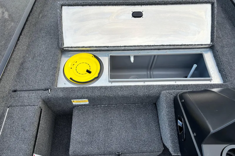 Slide: The Image of 2026 Crestliner 1700 Storm boat interior storage compartment with yellow lid and gray carpeting. - 3
