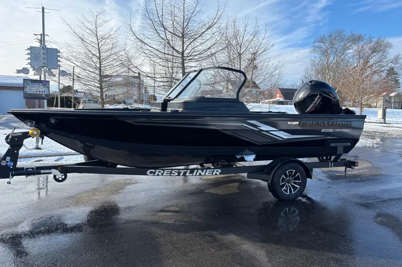 The Image of 2026 Crestliner 1850 Fish Hawk WT JS boat on trailer, parked on wet pavement. - 0