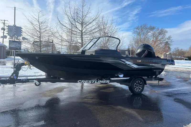 Slide: The Image of 2026 Crestliner 1850 Fish Hawk WT JS boat on trailer, parked on wet pavement. - 12