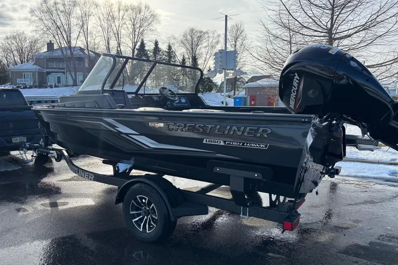 Slide: The Image of 2026 Crestliner 1850 Fish Hawk WT JS boat on trailer, parked in snowy setting. - 13
