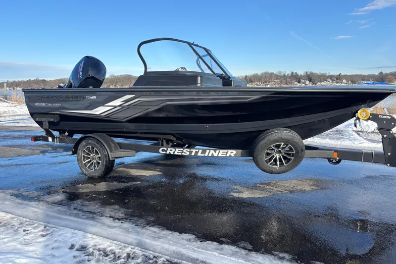 Slide: The Image of 2026 Crestliner 1850 Fish Hawk WT JS boat on trailer, parked on snowy ground. - 2