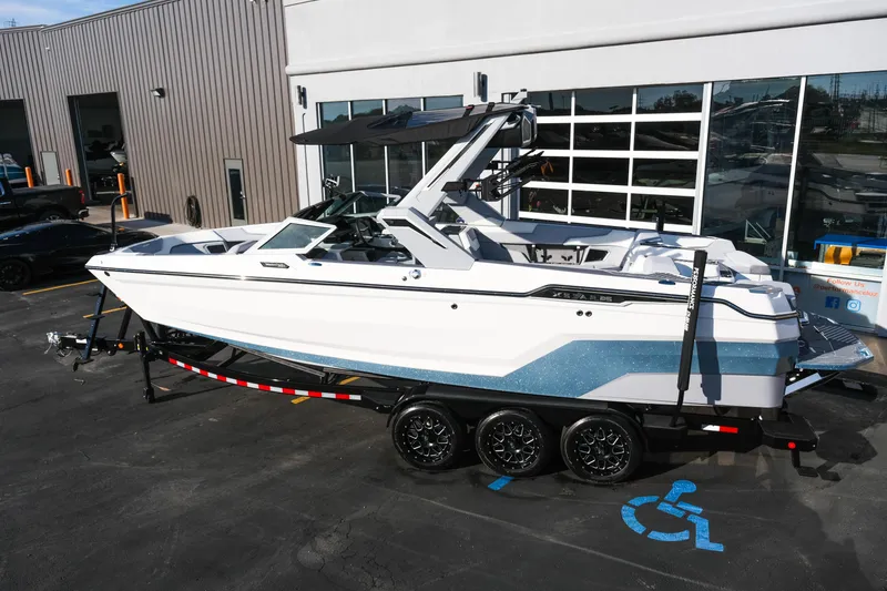 Slide: The Image of 2026 MasterCraft XStar 25 boat on trailer, parked outside a modern building. - 3