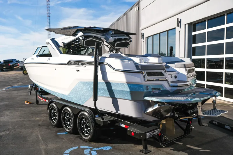 Slide: The Image of 2026 MasterCraft XStar 25 boat on trailer, parked outside a modern building. - 45