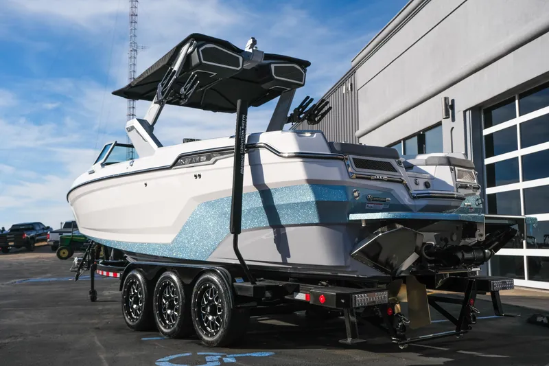 Slide: The Image of 2026 MasterCraft XStar 25 boat on trailer, parked outside a modern building. - 5