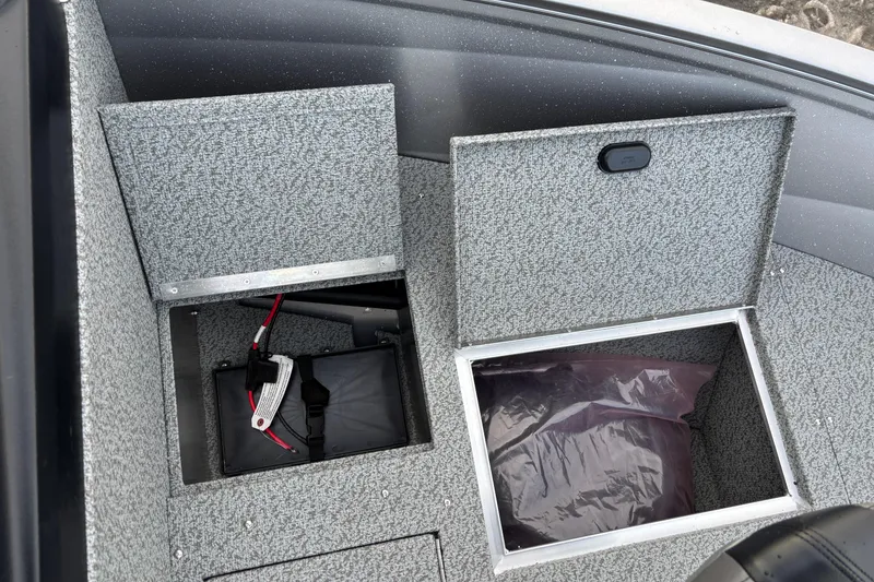 Slide: The Image of 2026 Crestliner 1650 Kodiak boat storage compartments with battery and protective cover. - 10