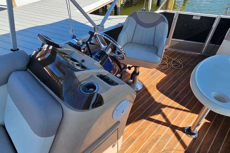 Slide: The Image of 2013 Crest 22 TriToon boat interior with steering console and seating on wooden deck. - 10