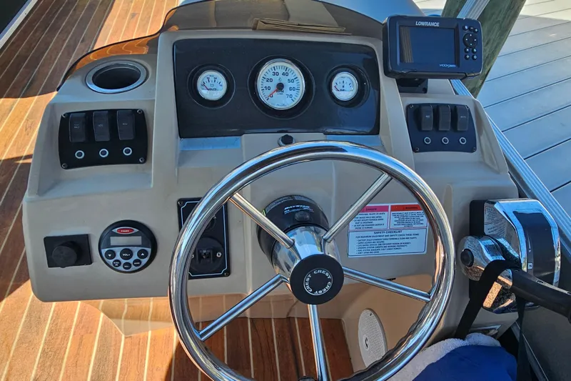 Slide: The Image of 2013 Crest 22 TriToon dashboard with steering wheel and controls, featuring Lowrance display. - 11