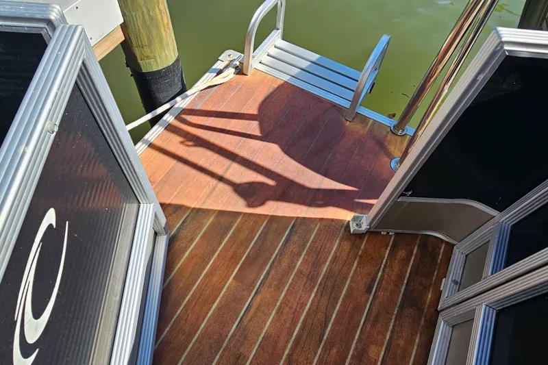 Slide: The Image of 2013 Crest 22 TriToon boat deck with wooden flooring and metal railing. - 12