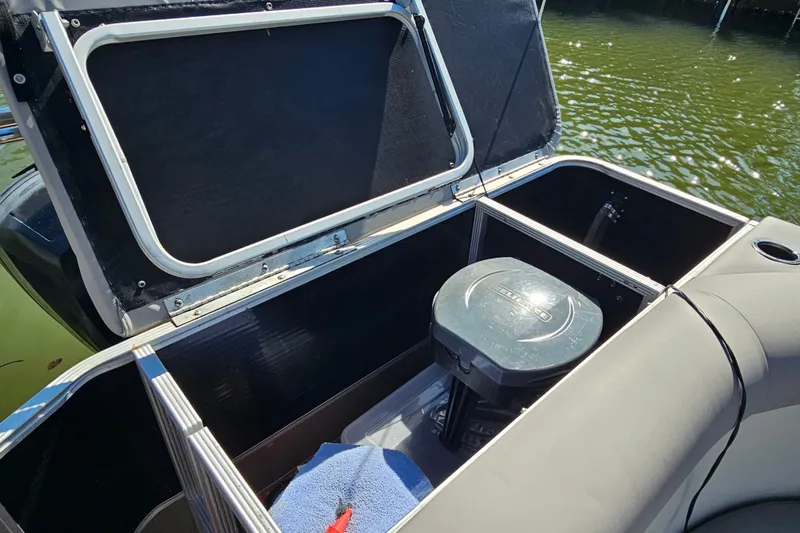 Slide: The Image of 2013 Crest 22 TriToon boat storage compartment with open hatch, docked on water. - 13
