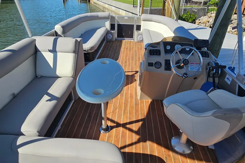 Slide: The Image of 2013 Crest 22 TriToon interior with seating, steering console, and table on wooden deck. - 15