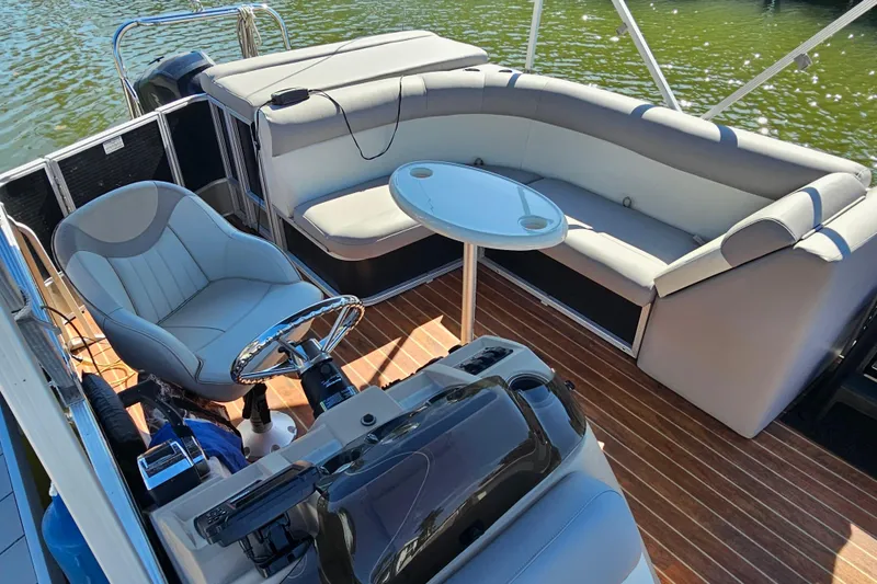 Slide: The Image of 2013 Crest 22 TriToon interior with seating, table, and steering wheel on water. - 4