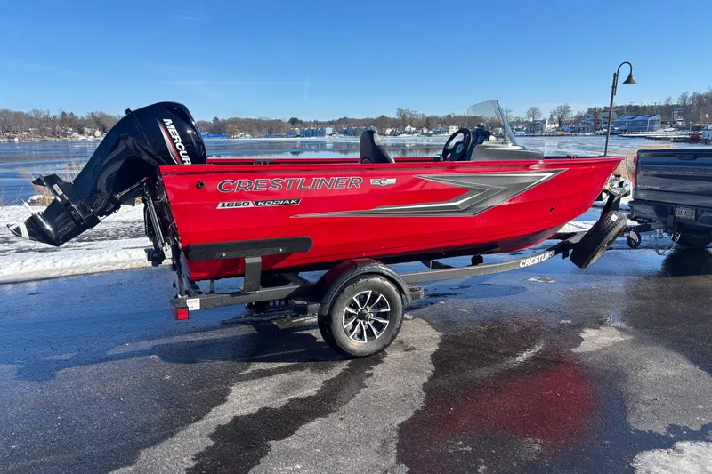 Slide: The Image of 2026 Crestliner 1650 Kodiak boat in vibrant red on a trailer by a lake. - 10