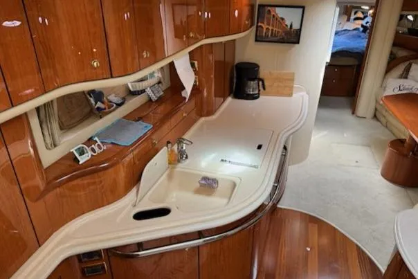 Slide: The Image of Interior of 2001 Sea Ray Sundancer 540 yacht, featuring a sleek kitchen with wooden cabinetry. - 6