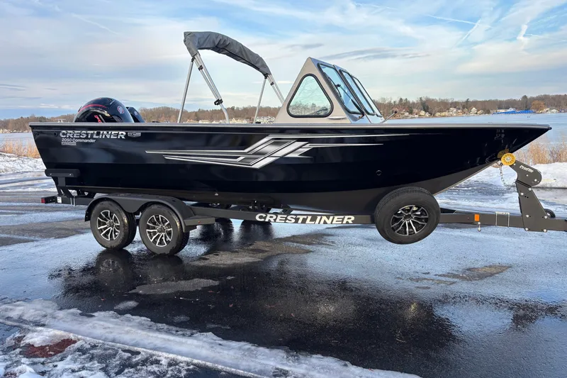 Slide: The Image of 2026 Crestliner 2050 Commander boat on trailer, parked near a snowy lake. - 0