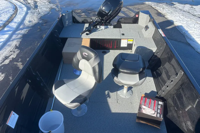 Slide: The Image of 2026 Crestliner 1650 Kodiak Tiller boat interior with seating and motor, parked on snowy pavement. - 5
