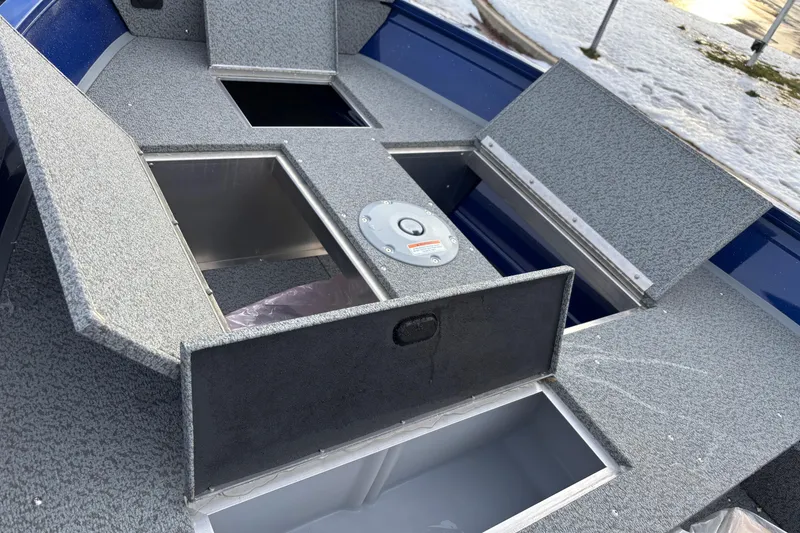 Slide: The Image of 2026 Crestliner 1650 Discovery Tiller boat with open storage compartments on a snowy day. - 2