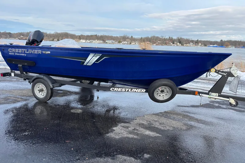 Slide: The Image of 2026 Crestliner 1650 Discovery Tiller boat on trailer by a lake. - 5
