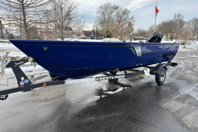 Slide: The Image of 2026 Crestliner 1650 Discovery Tiller boat on trailer, parked on wet pavement. - 6