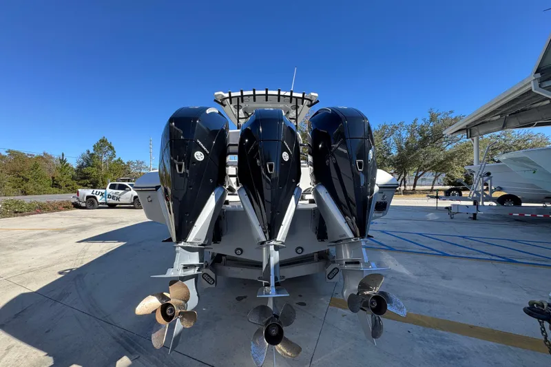 Slide: The Image of 2023 Fountain 34 Tournament Edition boat with triple outboard engines, docked under clear blue sky. - 13