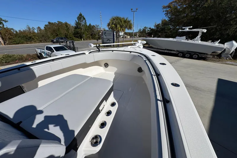 Slide: The Image of 2023 Fountain 34 Tournament Edition boat interior with seating and rod holders, parked outdoors. - 16