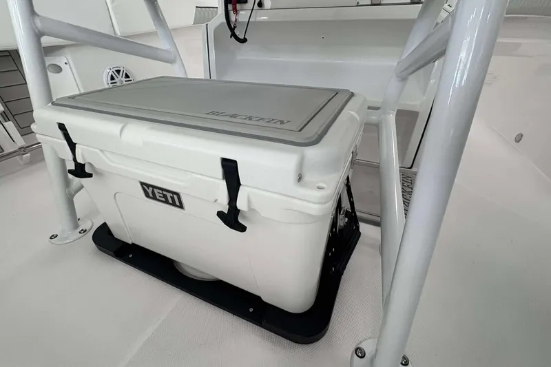 Slide: The Image of YETI cooler on 2026 Blackfin 222 CC boat deck, secured with black straps. - 17