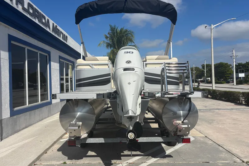Slide: The Image of 2026 Tahoe Pontoon 21 with outboard motor, parked outside a marine dealership. - 3