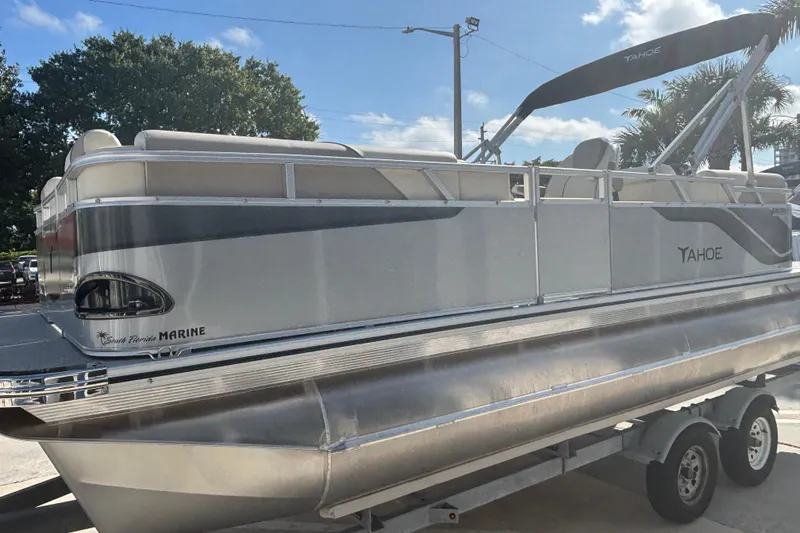 Slide: The Image of 2026 Tahoe Pontoon 21 boat on trailer, sunny day, palm trees in background. - 4