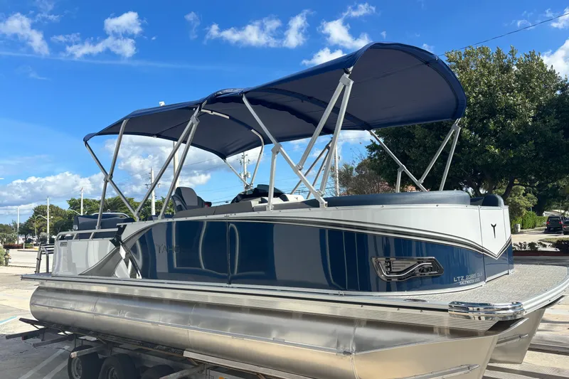 Slide: The Image of 2026 Tahoe Pontoons 23 LTZ Quad Lounge switch on trailer, under blue sky. - 4