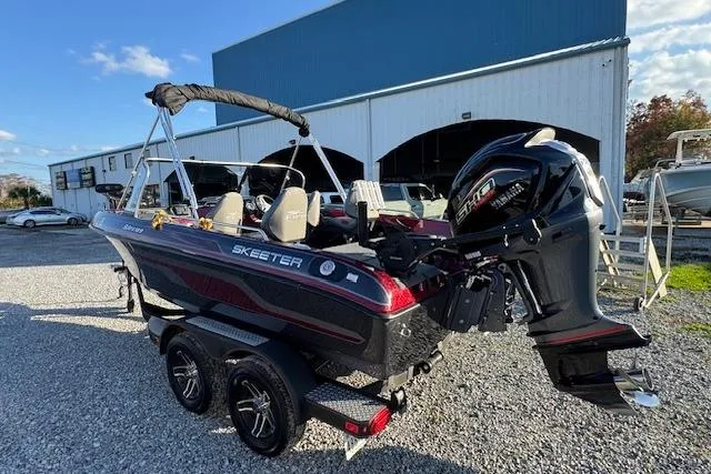 Slide: The Image of 2023 Skeeter Solera 189 boat with powerful outboard motor, parked on gravel near a warehouse. - 7
