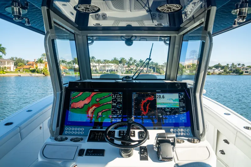 Slide: The Image of 2025 Costa Custom Boats 34 cockpit with advanced navigation displays on a serene waterway. - 12