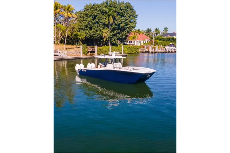 Slide: The Image of 2025 Costa Custom Boats 34 model on serene water near a dock, surrounded by lush greenery. - 2
